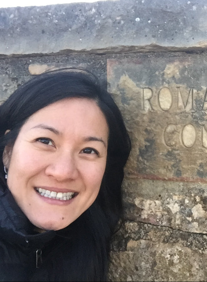 Daphne Feng smiling in front of a stone wall with 'Romanee Conti' inscription